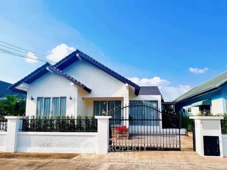 Charming single-story house with gated entrance and lush garden in a serene neighborhood.