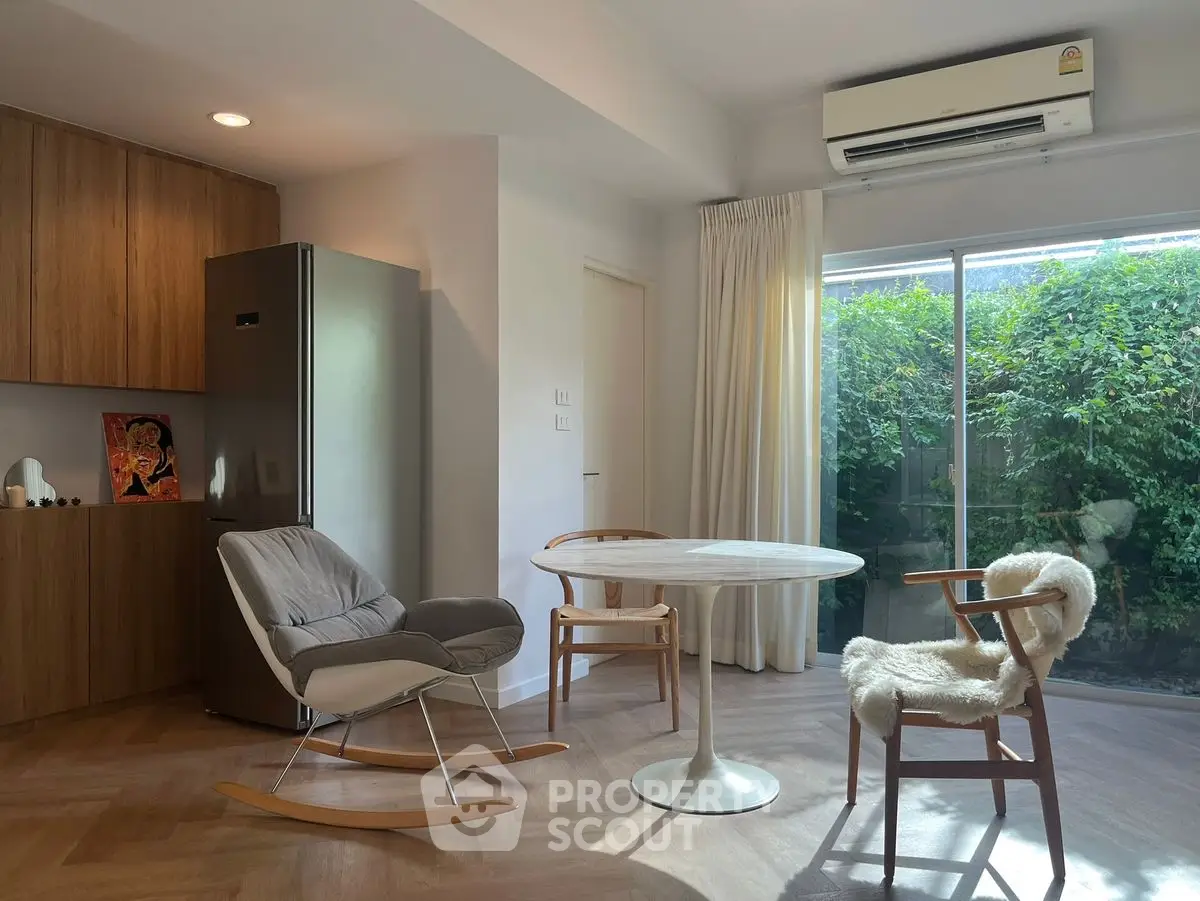 Modern living room with stylish furniture and large window overlooking greenery.