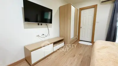 Modern bedroom with wall-mounted TV and wooden furniture, showcasing sleek design and cozy ambiance.