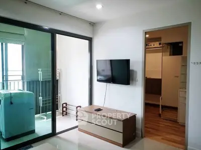 Modern living room with wall-mounted TV and balcony access in stylish apartment.