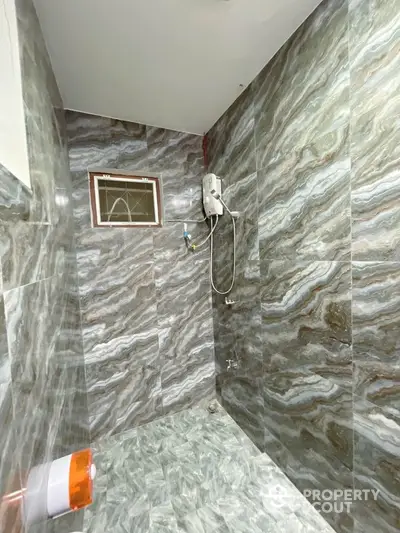 Modern bathroom with marble tiles and shower in stylish real estate property.