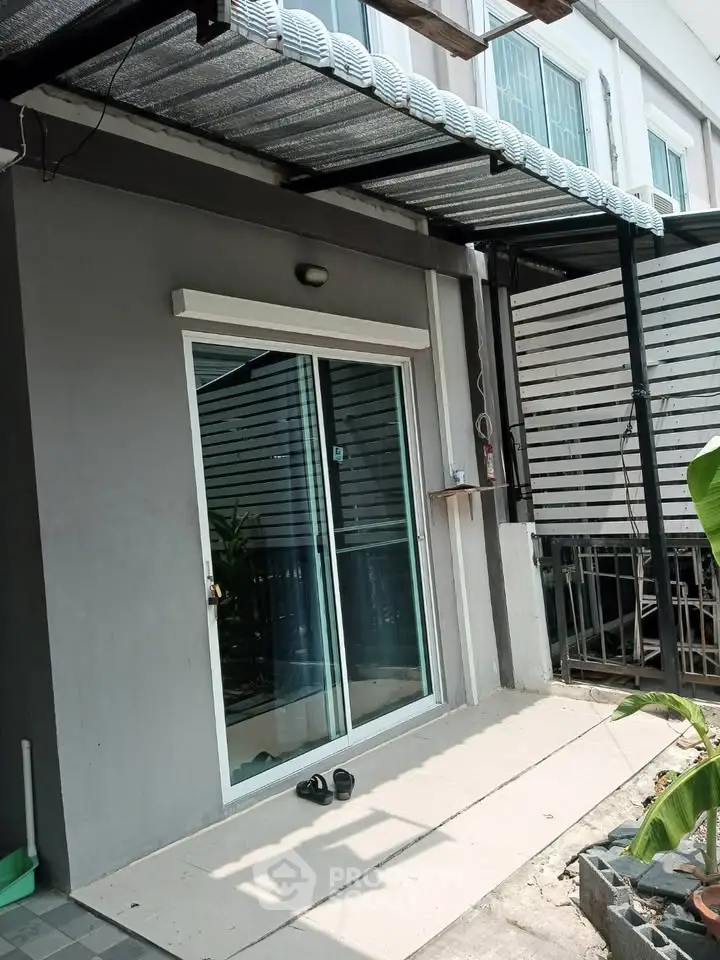 Modern townhouse exterior with sliding glass doors and covered entrance.