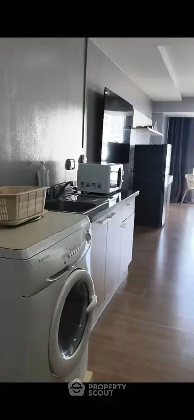 Modern kitchen with washing machine and sleek appliances in open layout apartment.