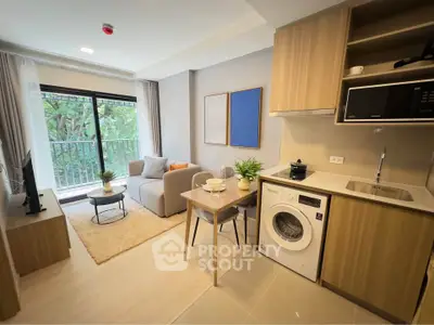 Modern open-plan living room with kitchen, featuring washing machine and balcony view.