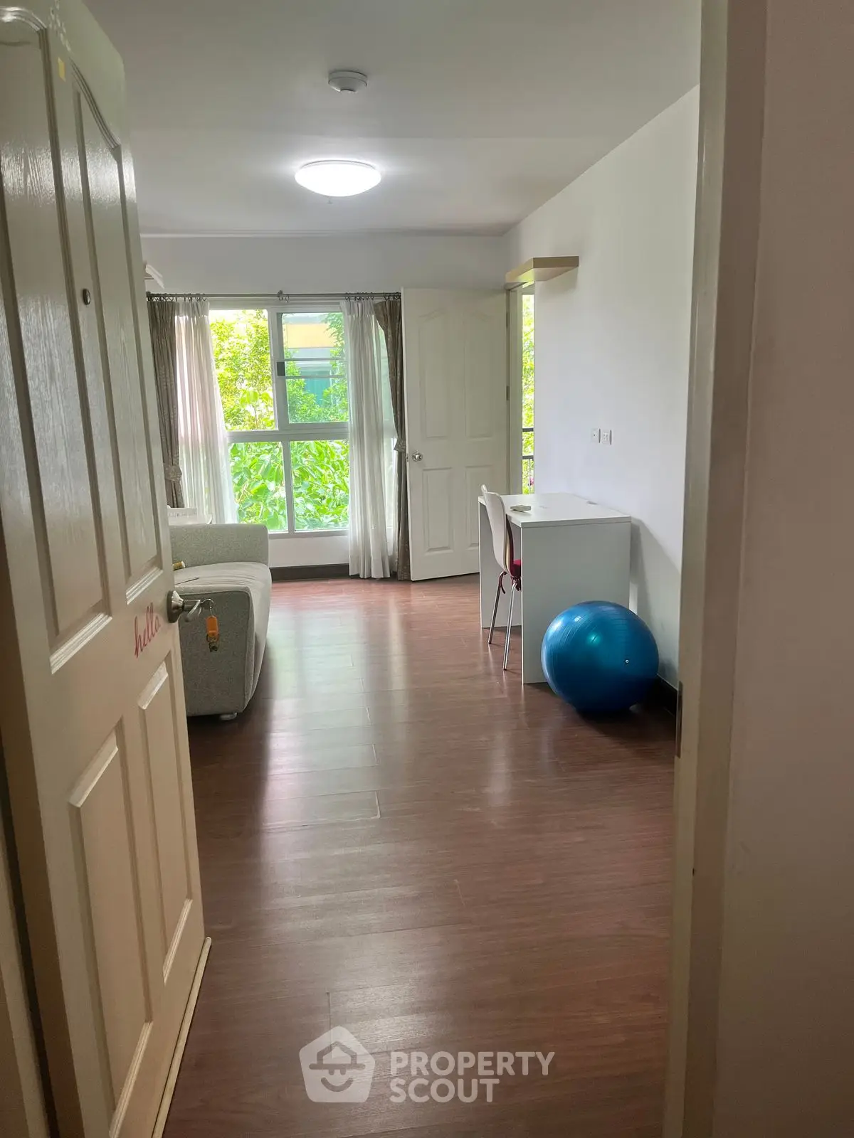Spacious living room with large window and wooden flooring, perfect for relaxation and natural light.