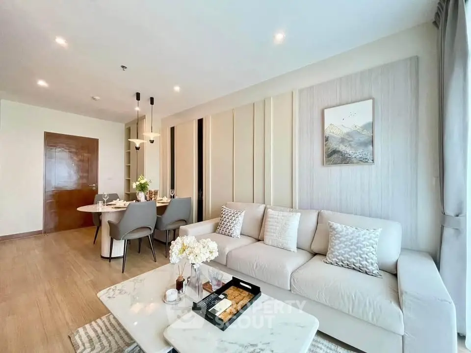 Elegant living room with modern decor and dining area, featuring a cozy sofa and stylish lighting.