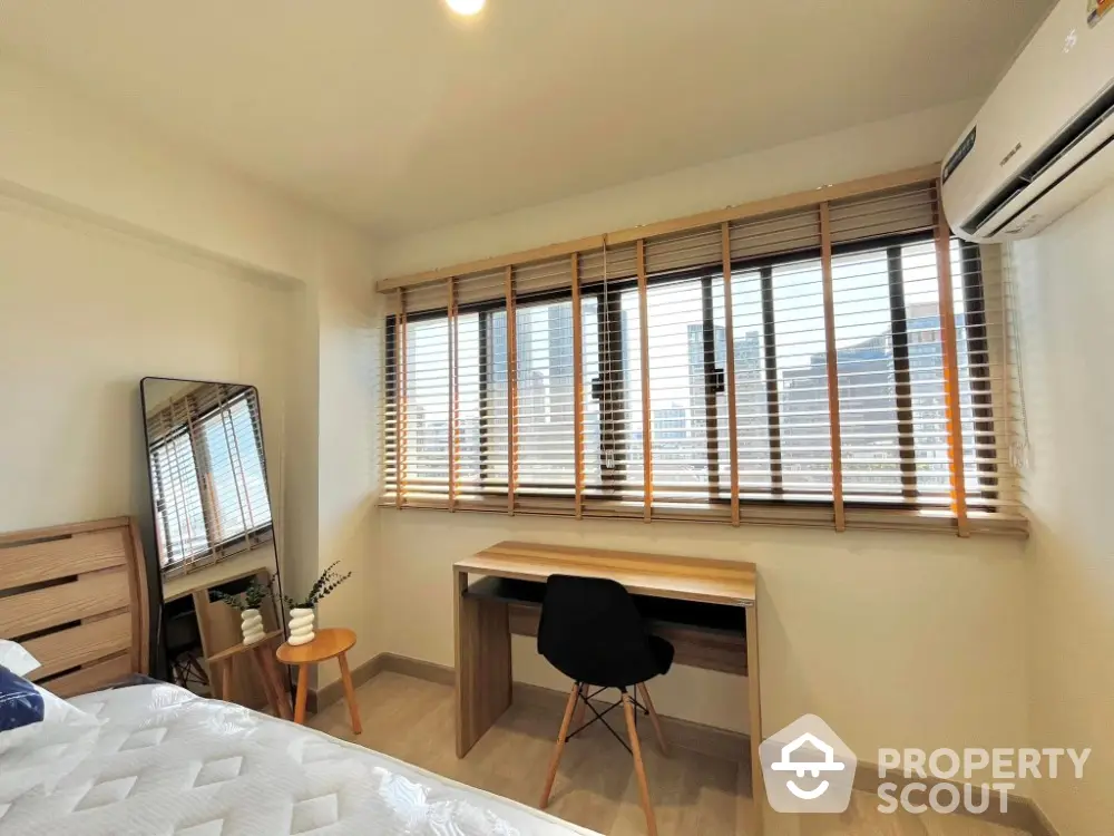 Bright bedroom with city view, featuring a desk and modern decor.