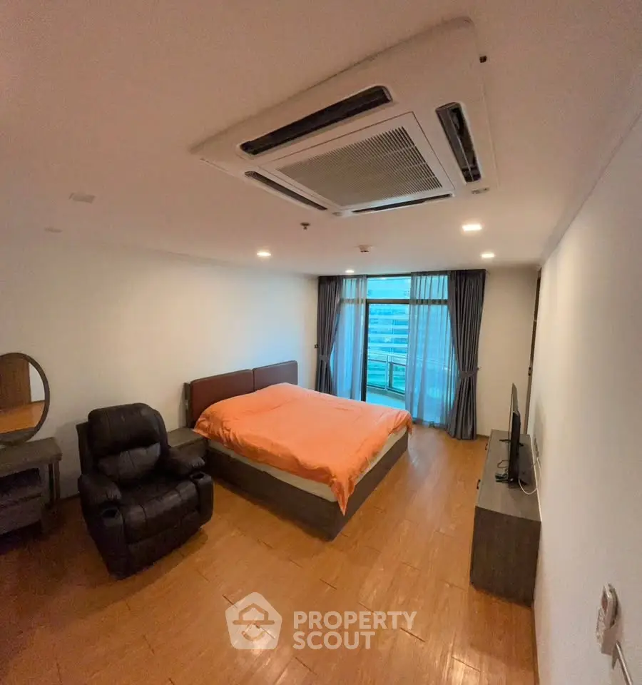 Spacious bedroom with modern furnishings and large window view