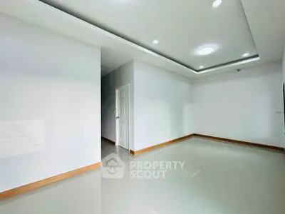 Spacious empty room with modern ceiling lights and glossy tiled floor