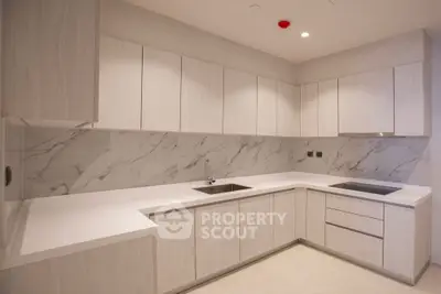 Modern kitchen with sleek cabinetry and marble backsplash in a luxurious home.