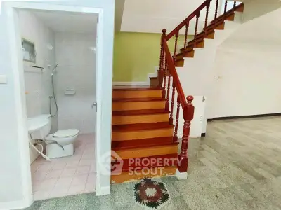 Charming interior with wooden staircase and adjacent bathroom, perfect for cozy living.