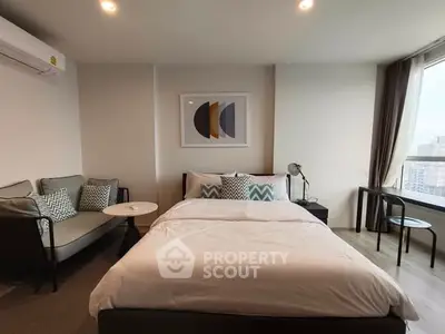 Modern bedroom with stylish decor and city view, featuring cozy seating area and natural light.