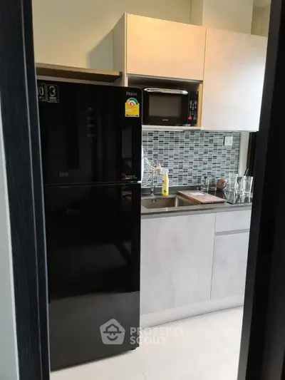 Modern kitchen with sleek black fridge and stylish backsplash