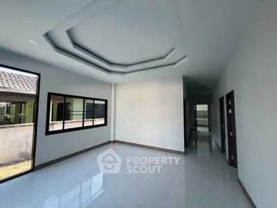 Spacious modern living room with large windows and elegant ceiling design in a contemporary home.