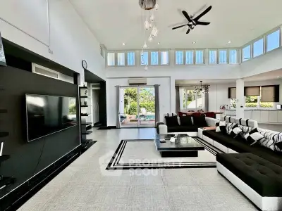 Spacious modern living room with high ceilings and stylish decor, featuring a large TV and elegant seating area.