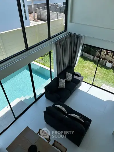 Luxurious living room with pool view and high ceilings, perfect for modern living.
