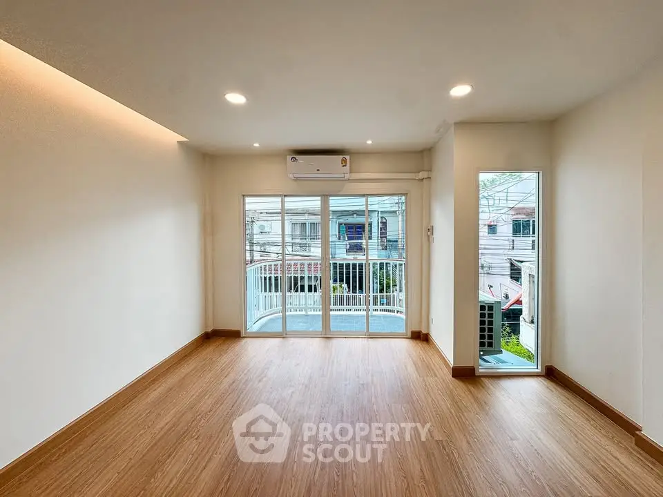 Spacious living room with wooden flooring and balcony access