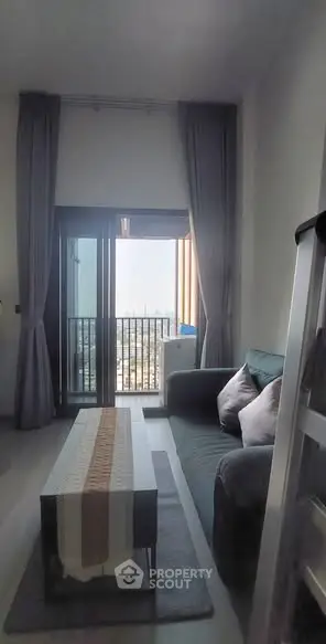 Modern living room with balcony and city view, featuring cozy sofa and elegant decor.