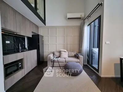 Modern living room with open kitchen, featuring sleek design and cozy seating area.