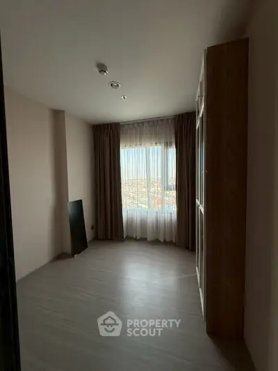 Spacious room with large window offering stunning city view, ideal for bedroom or study.