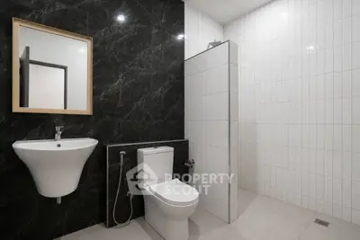 Modern minimalist bathroom with sleek black and white tiles and contemporary fixtures.