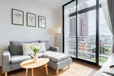 Modern living room with large windows and city view, featuring stylish decor and comfortable seating.