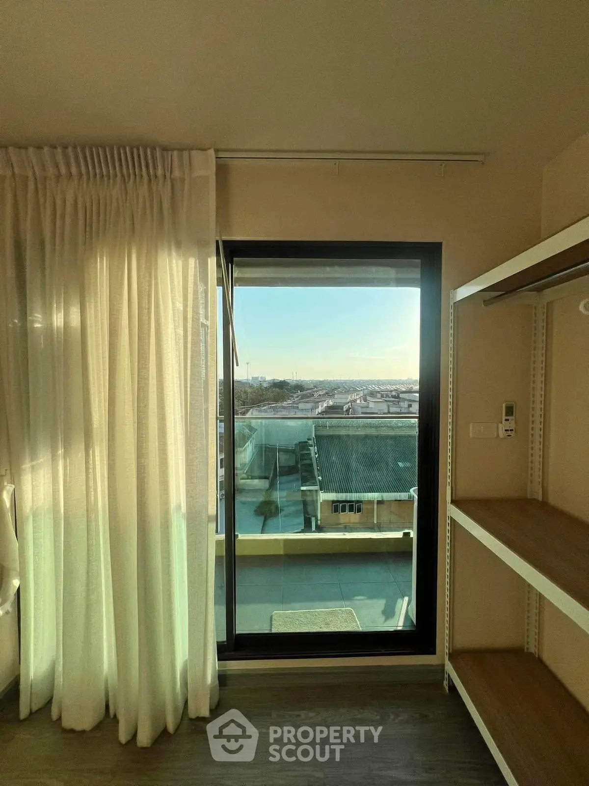 Bright room with large window and balcony offering stunning city view, perfect for modern living.