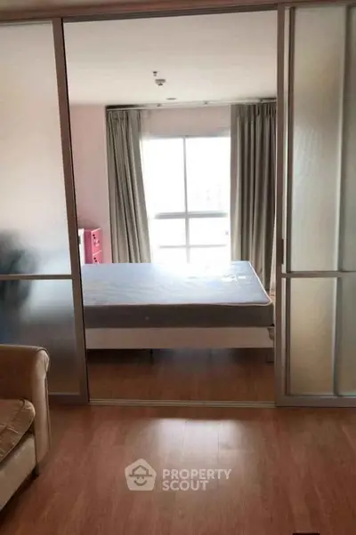 Spacious bedroom with large window and sliding glass doors, perfect for natural light.