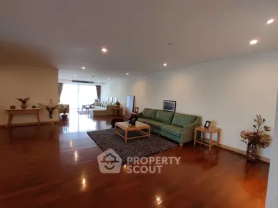Spacious living room with elegant decor and hardwood flooring, featuring cozy seating and natural light.