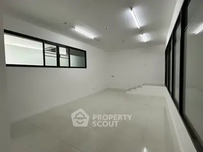 Spacious modern room with white tiles and large windows, ideal for office or studio setup.