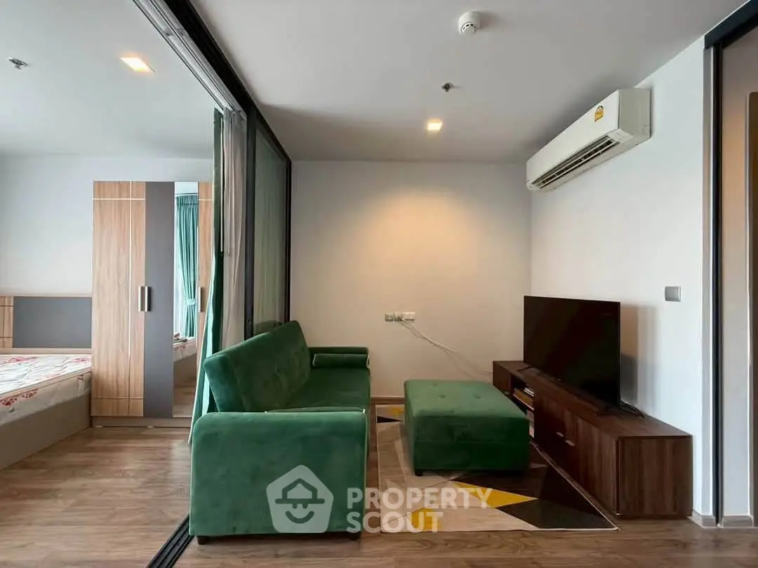 Modern living room with green sofa, TV, and air conditioning in a stylish apartment.