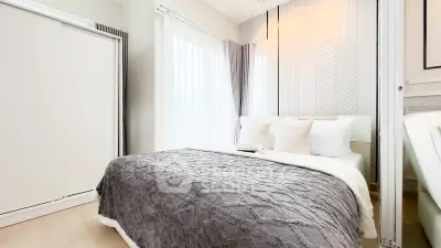 Modern bedroom with cozy decor and natural light, featuring stylish bedding and elegant curtains.