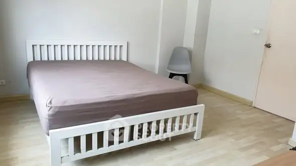 Minimalist bedroom with wooden flooring and modern white bed frame.