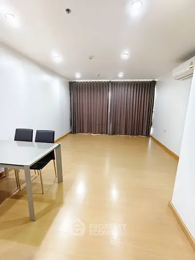 Spacious empty living room with wooden flooring and large window curtains