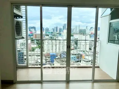 Stunning city view from modern apartment balcony with sliding glass doors.