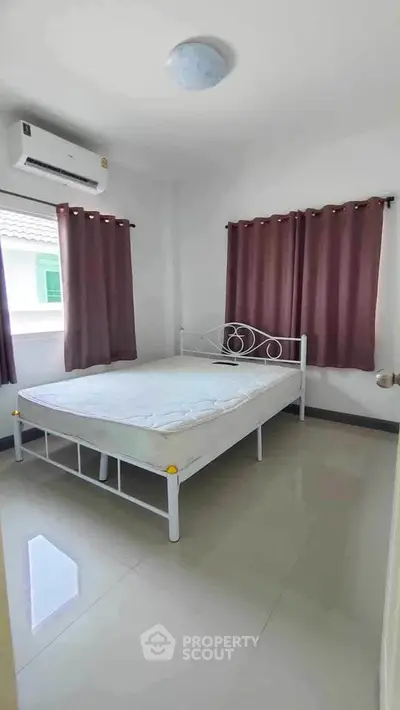 Cozy bedroom with natural light and minimalist decor, featuring a comfortable bed and air conditioning.