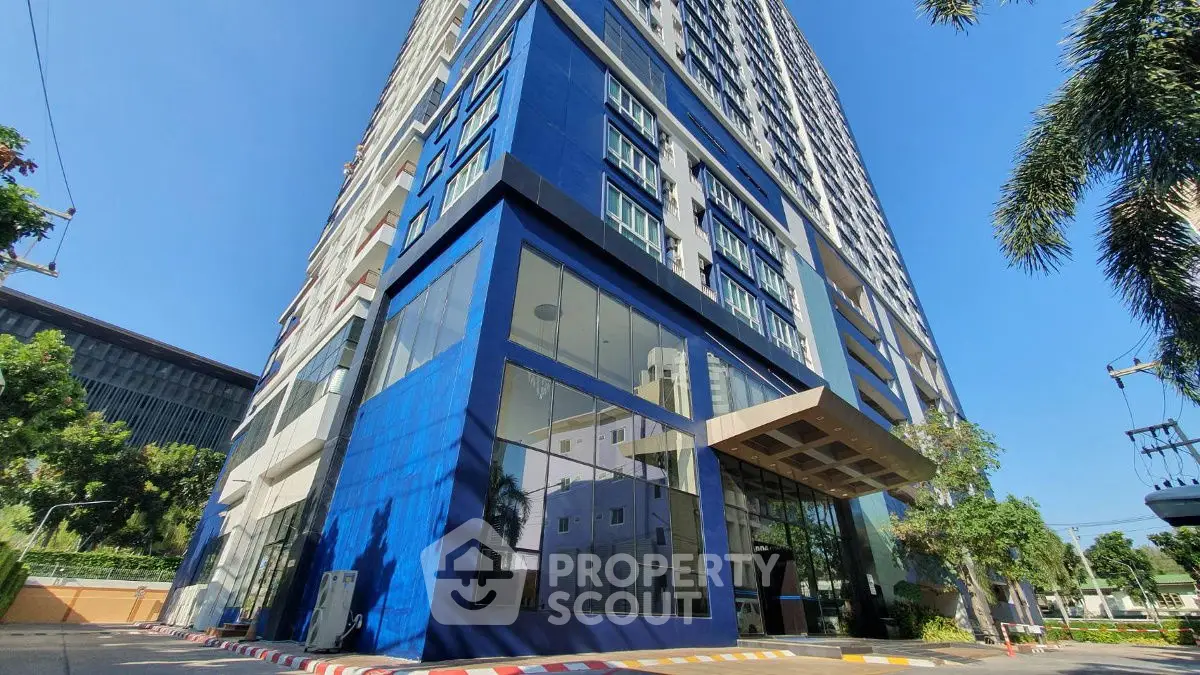 Modern high-rise building with blue facade and glass entrance in urban setting