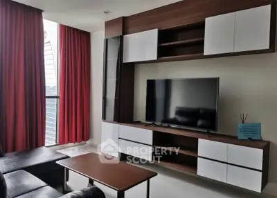 Modern living room with sleek TV unit and red curtains in a stylish apartment.