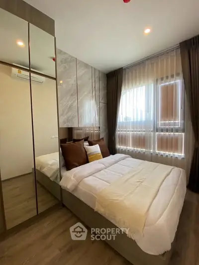 Modern bedroom with stylish decor, large mirrored wardrobe, and natural light from floor-to-ceiling windows.