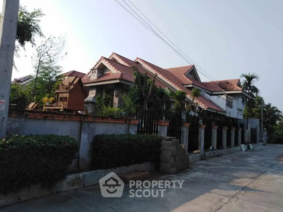 Charming suburban house with red-tiled roof and lush greenery, offering a serene residential atmosphere.