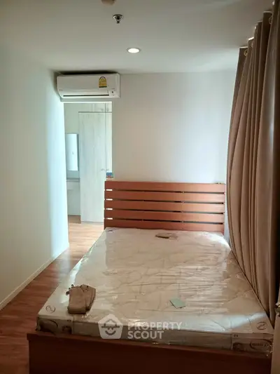 Cozy bedroom with wooden flooring and air conditioning in modern apartment.