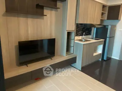 Modern compact living room with integrated kitchen, featuring sleek cabinetry and a flat-screen TV.