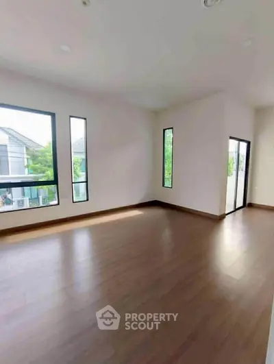 Spacious empty room with large windows and wooden flooring, perfect for customization.