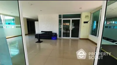 Spacious modern building entrance with sleek glass doors and polished tile flooring.