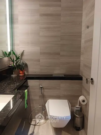 Modern bathroom with sleek design and high-end fixtures, featuring a wall-mounted toilet and elegant vanity.