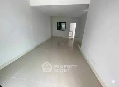 Spacious empty room with glossy tiled flooring and white walls, ideal for customization.