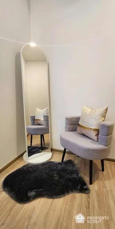 Cozy corner with stylish chair and full-length mirror on wooden floor