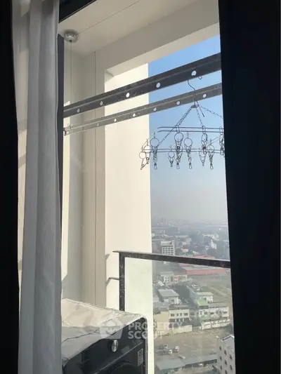 High-rise apartment balcony with city view and laundry drying rack
