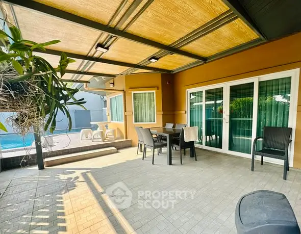 Spacious patio with outdoor dining set and pool view, perfect for entertaining.