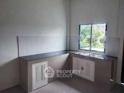 Modern kitchen with sleek countertops and garden view window, perfect for culinary enthusiasts.